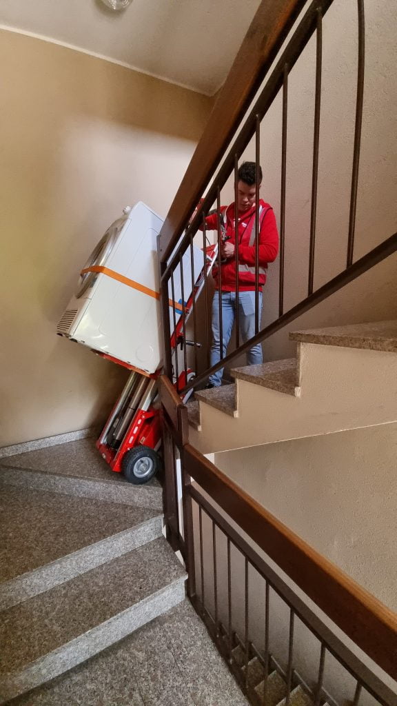 Un hombre transporta una lavadora por las escaleras con el sube escaleras eléctrico Buddy Lift Plasmoid